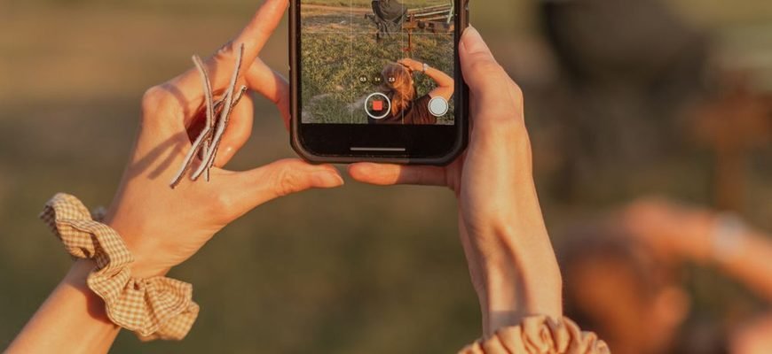 Руки тримають смартфон і знімають вертикальне відео
